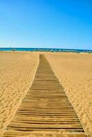 un de madera pasarela Guías a el playa en un soleado día foto