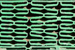 a close up of a green grate with many holes photo
