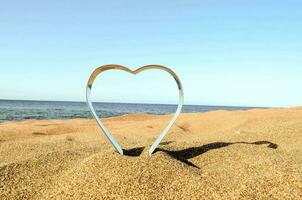 a heart shaped metal object on the beach photo