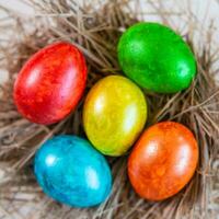 Multi-colored Easter eggs lie together on a straw in the form of a nest on a white background. Happy easter photo