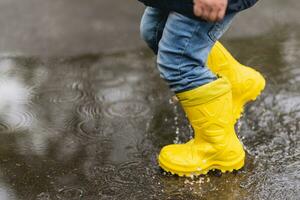 little boy walks through the puddles in the spring after the rain photo