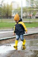 little boy walks through the puddles in the spring after the rain photo