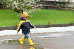 little boy walks through the puddles in the spring after the rain photo