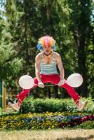 Mime jumps in the park with balloons. Clown in the air shows pantomime on the street. photo