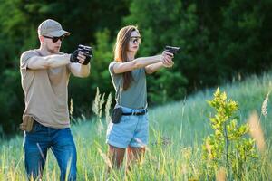 the instructor teaches the girl to shoot a pistol at the range photo