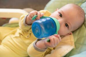 The baby drinks water from a bottle. photo