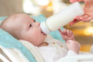 mother gives baby milk from a bottle at home photo