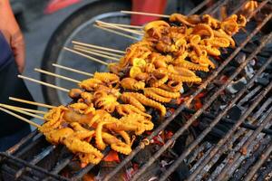 Exotic asian food, grilled squid stuffed with seafood. Grilled squid on a charcoal stove. Thai street food style squid on a stick on the grill. photo