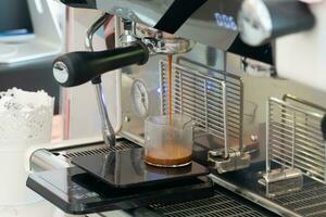 el proceso de haciendo café paso por paso. mujer apisonar recién suelo café frijoles en un portafiltro un café tostador comprobación un café muestra desde un café tostador máquina. foto