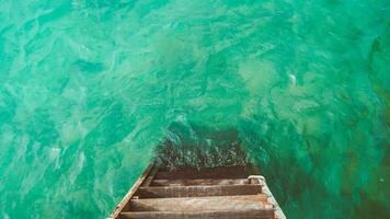 vacío muelles. de madera escalera yendo dentro el mar con pequeño olas y turquesa agua. foto