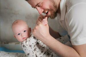 papá es jugando con su bebé. padre sostiene el manos de un recién nacido hijo foto