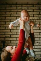 The mother lifts the baby above her head . The mom raise up in her hands child. A young woman has fun and rejoices with the infant. photo