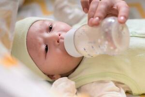 young mother feeds her baby milk from a bottle photo