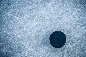 black hockey puck lies on ice at stadium photo