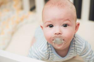 The baby lies in a crib on his tummy. photo