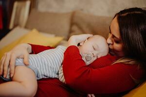 The baby sleeps on the mother's chest and stomach. Mom kisses and hugs the child. photo