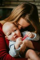 A mother holds a baby in her arms. A mom kisses a infant. A women hugs her toddler. A girl has fun and rejoices with the child. photo