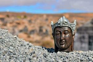 a statue of a buddha head on top of a pile of rocks photo