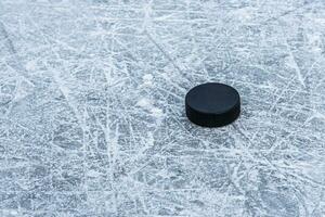 black hockey puck lies on ice at stadium photo