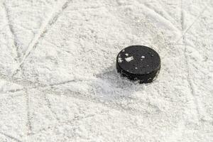 hockey puck lies on the snow close-up photo