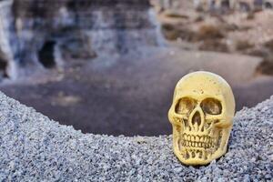 a yellow skull sitting on top of a rocky cliff photo