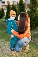 un madre y un niño en médico mascaras caminar en el calle durante el coronavirus y covid-19 pandemia. foto