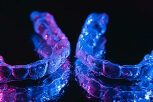 Transparent aligners, tooth retainers lie on a mirror with water droplets on a black background photo