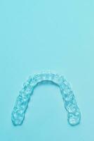 Invisible dental teeth brackets tooth aligners on turquoise background. Plastic braces dentistry retainers to straighten teeth. photo