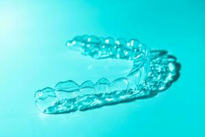 Invisible dental teeth brackets tooth aligners on blue background. Plastic braces dentistry retainers to straighten teeth. photo