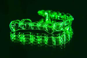 Invisible dental teeth brackets tooth aligners on black background. Plastic braces dentistry retainers to straighten teeth. photo