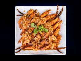 Crispy prawns in tamarind sauce in  white square dish, sprinkle with glaze and top with fried shallots and coriander. It has perfect balance of crispy, spicy, and sweet flavors. photo
