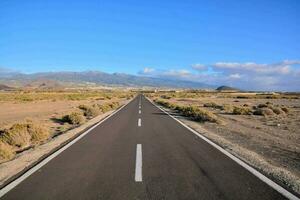 an empty road in the middle of a desert photo