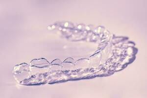 Invisible aligner teeth retainers on a pink background photo