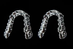 Invisible aligner teeth retainers on a black background photo