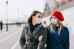 Two girls in medical masks are walking down the street. Protection against coronavirus Covid-19 during quarantine photo