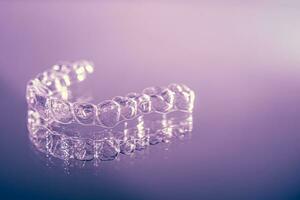 Invisible dental teeth brackets tooth aligners on pink background. Plastic braces dentistry retainers to straighten teeth. photo