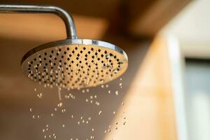 Close up to Outdoor shower head for the bath and showering cold water to body before jumping in the resort pool. photo