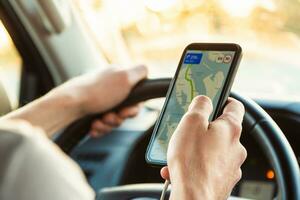 A tourist is sitting in a car and looking for the road in the Navigator app on a Sunny day photo