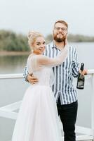 joven recién casados abrazando en el muelle por el agua. foto