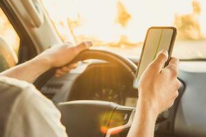 A man sits in a car and looks at his phone with the Navigator app on a Sunny day photo