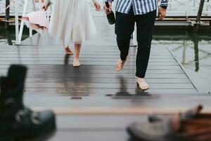 Feet of the newlyweds on the background of the pier.The bride and groom go barefoot along the wharf. photo