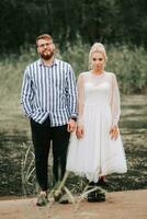 Young newlyweds stand on the background of the river and pose. photo