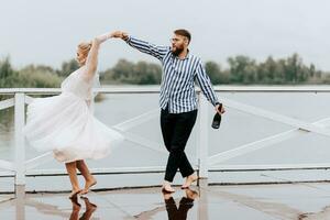 Beautiful just married dance barefoot and have fun on the pier by the water. photo