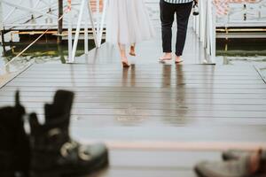 Feet of the newlyweds on the background of the pier.The bride and groom go barefoot along the wharf. photo