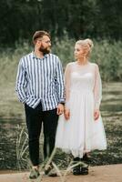 Beautiful just married stand on the background of the lake and pose. photo