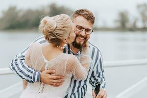 Young newlyweds kissing and hugging on the pier by the water. photo