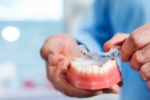 Close-up. The doctor puts transparent aligners on the teeth of the artificial jaw photo