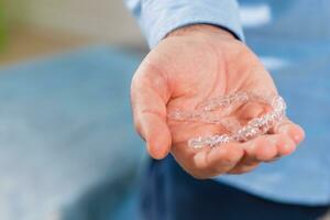 The orthodontist doctor holds transparent aligners in his hands photo