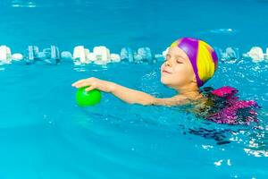 A little boy with a life jacket on his chest learns to swim in an indoor pool. photo