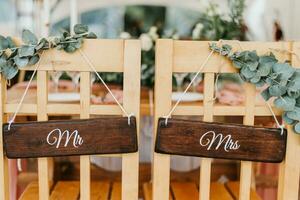 Chairs for bride and groom decorated with flowers with signs mr and mrs for wedding ceremony photo